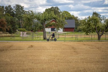 Güneşli bir günde elektrikli scooterlı bir adamın güzel manzarası. İsveç. Uppsala. 08.29.2021.