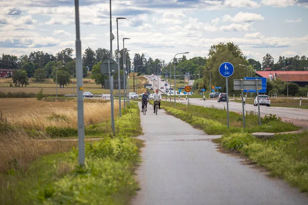 Güzel şehir manzarası iki bisikletçinin ve arabaların yolda olduğunu gösteriyor. İsveç. Uppsala. 08.29.2021.