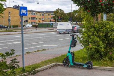 Otoparkta motosiklet için park edilmiş elektrikli scooter manzarası. İsveç. Uppsala. 09.08.2021.