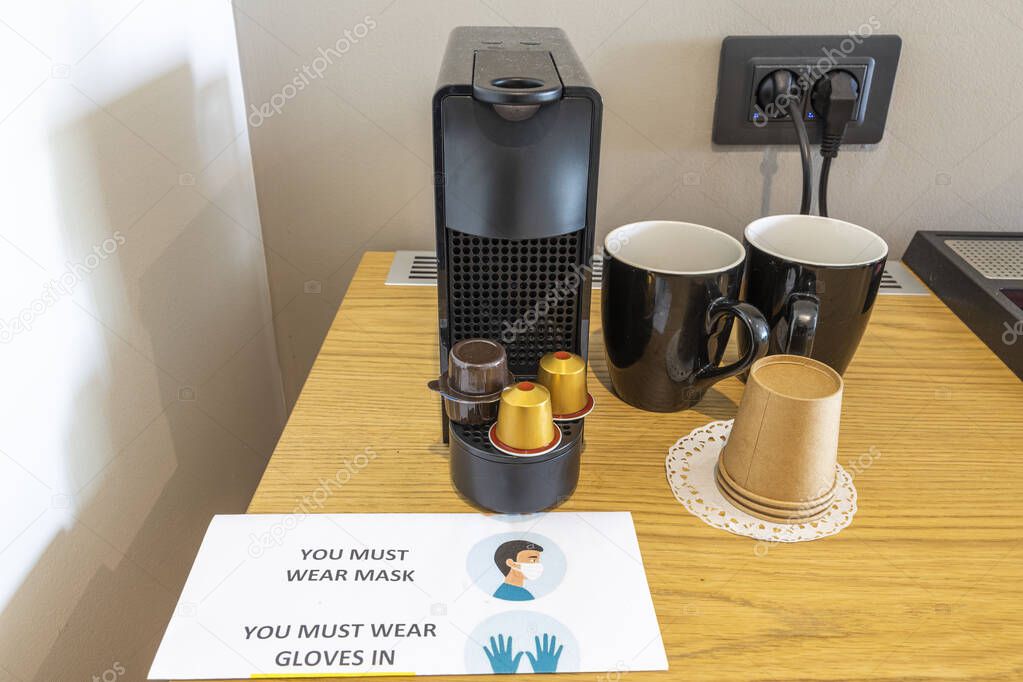 Click up view of coffee capsule machine and two cups on wooden table in hotel room. Greece. 