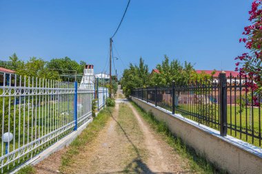 Tipik köy sokağı ve her iki tarafında metal çitler olan yol manzarası çok güzel. Yunanistan.