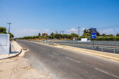 Mavi gökyüzü ile birleşen otobanın güzel manzarası. Kamp ve sahile giden yol tabelası. Yunanistan. 