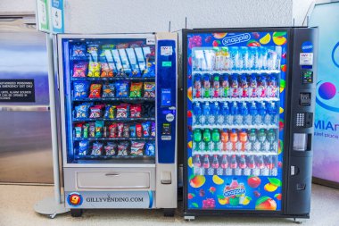 Close up view of vending machines with snacks and Snapple drinks standing in bright airport terminal. Miami. USA.