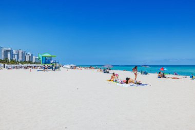 İnsanlar cankurtaran kulesi olan kumlu Miami Plajı 'nda rahatlıyor ve arka planda Atlantik Okyanusu' nu sakinleştiriyor. Miami Plajı. ABD. 