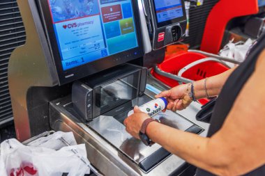 Chobani yoğurt içeceğini CVC 'de tarayan bir kadının süpermarkette kasaya girişini yakından izleyin. Miami Plajı. ABD. 