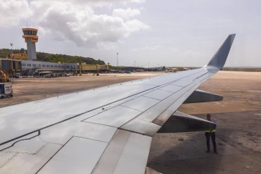 Uçak kanadı manzarasını kapatın. Havaalanı çalışanı pistte motorun yanında duruyor..