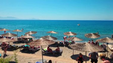 Ege Denizi kıyısındaki kumsalda saman şemsiyeleriyle dinlenen turistler. Kos. Yunanistan. 