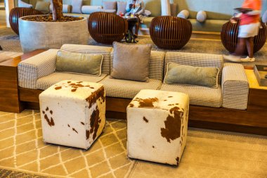 Modern otel lobisinin iç dekorasyonunda şık bir kanepe ve arka planda iki sığır derisi tabure var. Meksika mı? Cancun..