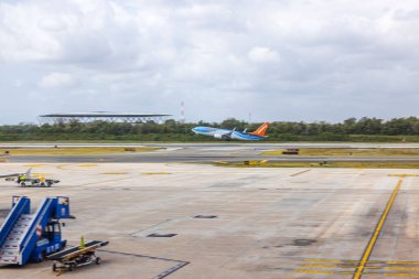 Sunwing Havayolları uçağı bulutlu gökyüzünün arka planında havaalanından kalkıyor. Meksika mı? Cancun.. 