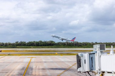 Hava alanından kalkan American Airlines uçağı bulutlu gökyüzünün arka planında. Meksika mı? Cancun.. 