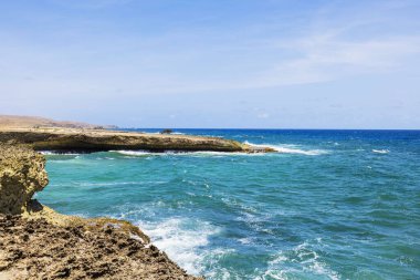 Arikok Ulusal Parkı 'nda açık mavi arka planda kayalık kıyılara vuran turkuaz Karayip Denizi dalgalarının güzel manzarası. Aruba.
