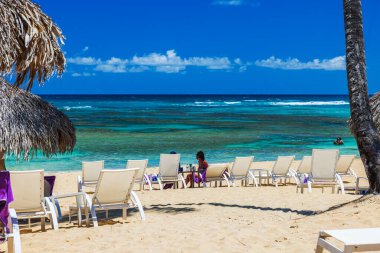 Kumlu sahilde turkuaz Atlantik Okyanusu 'na bakan plaj sandalyelerinin güzel manzarası ve arka planda turistler. Punta Cana. Dominik Cumhuriyeti. 