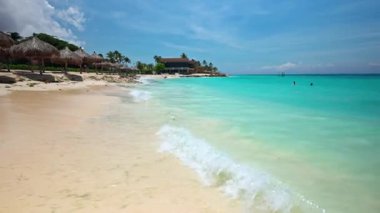 Karayip Denizi 'ndeki Kartal Sahili' nin muhteşem manzarası dalgalar, yumuşak kum, palmiye yaprağı şemsiyeleri ve insanlarla dolu.. 