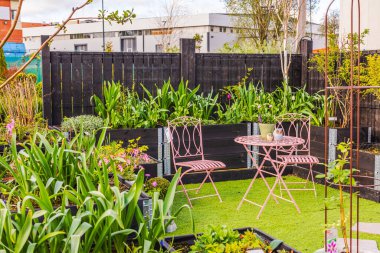 Pembe sandalyeli ve yemyeşil bitkilerle alışveriş merkezindeki bahçe tasarımının güzel manzarası..