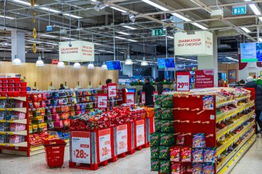 Şekerleme vitrinleri ve alışveriş yapan müşterilerin bulunduğu süpermarketin kişisel kontrol bölgesini kapat. 