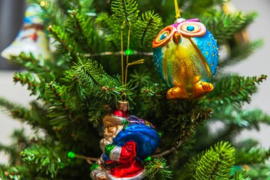 Noel baykuşu süsü ve Noel Baba figürünün yeşil dallarda asılı görüntüsü. İsveç.