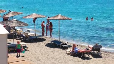 Ege Denizi 'nin arka planında dinlenen turistlerin olduğu güzel bir çakıl taşı sahili manzarası. Yunanistan. Kos.