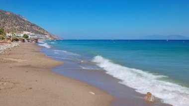 Ege Denizi 'nin muhteşem manzarası arka planda dağlarla birlikte çakıllı sahil boyunca yuvarlanıyor. Yunanistan.