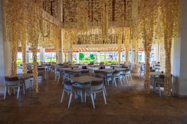 Arka planda deniz kabuğu masaları ve sandalyeler olan tropikal bir restoran manzarası. Dominik Cumhuriyeti. Punta Cana. 