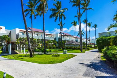 Palmiye ağaçları, yeşil çimenler ve modern otel binaları olan tropikal tatil köyünün güzel manzarası. Dominik Cumhuriyeti. Punta Cana. 
