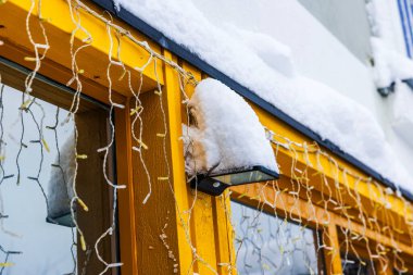 Kış boyunca karla kaplı ve çelenk lambalarıyla kaplı villa ön cephe lambasının yakın görüntüsü. İsveç.