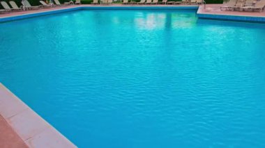 Güneşli bir günde tatil köyünde berrak mavi yüzme havuzu yüzeyi ve hafif dalgalanmalar. Yunanistan.