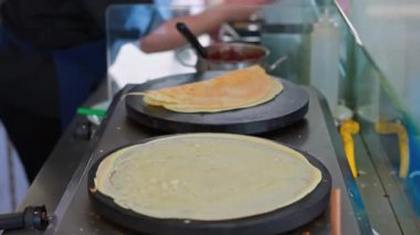 Sıcak ızgaranın üzerindeki krep pişirme manzarasını kapatın ve sokak yemeği hazırlıkları sırasında sos eklensin. Yunanistan.