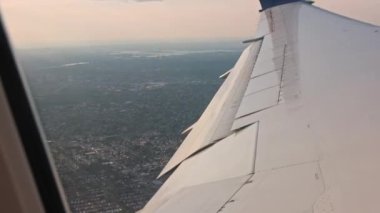Uçak kanadı, uçuş sırasında şehir manzarasının üstündeki pencereden çok güzel görünüyor. ABD.