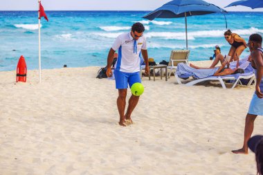 Kumlu Karayip Denizi yazlığında turistlerle futbol oynayan otel çalışanlarının güzel manzarası. Cancun. Meksika.