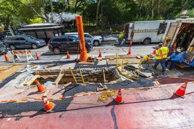 Close up view of workers repair underground utilities at an active road construction site. New York. USA.