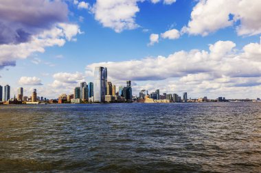 Magnificent panoramic skyline of Manhattan across Hudson River against blue sky with white clouds. New York. USA.