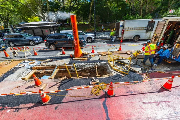 Close up view of workers repair underground utilities at an active road construction site. New York. USA.