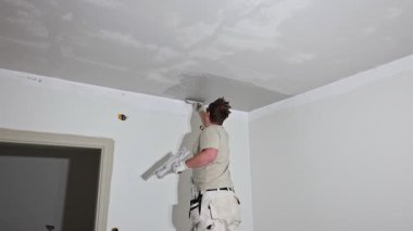 Dairenin iç dekorasyonu sırasında tavan köşesine alçı yapıştıran işçinin yakın görüntüsü.