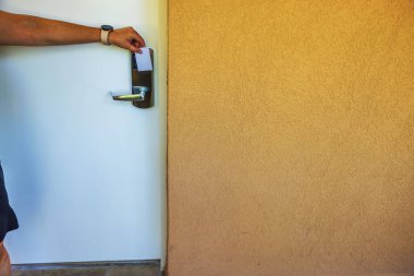 Otel odasının kapı kilidinin yakınındaki el ele tutuşan anahtar kartının görüntüsünü, dokulu duvar arka planına yakın tut. Aruba.