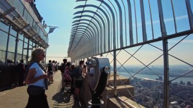 Empire State Binası gözlem güvertesinde dürbün kullanan turistlerin güzel manzarası ve arka planda şehir silüeti. - New York. ABD.