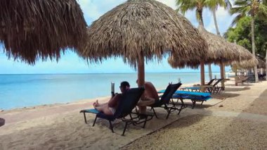 Karayip Denizi yakınlarındaki plaj şemsiyelerinin altında dinlenen turistlerin güzel manzarası..