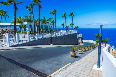 Atlantik Okyanusu 'nun arka planında palmiye ağaçları ve terası olan otelin giriş yolu ve açık mavi gökyüzü çok güzel. Büyük Kanarya. İspanya.