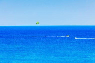 Ege Denizi üzerindeki deniz paraşütünün güzel manzarası. Açık mavi gökyüzüne karşı hareket eden motorlu tekne. Yunanistan. Rodos.