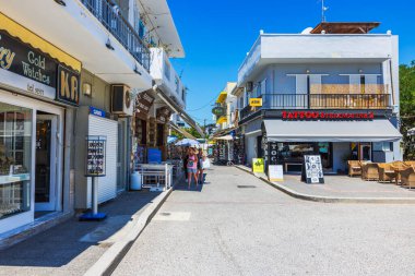 Hediyelik eşya dükkanları, kafeler, dövme stüdyosu ve tatil köyünde yürüyen yayalar olan güzel bir sokak manzarası. Kardamena. Yunanistan.
