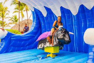 Tropikal tatil köyünde mekanik boğaya binen kadını yakından izleyin. Punta Cana. Dominik Cumhuriyeti.