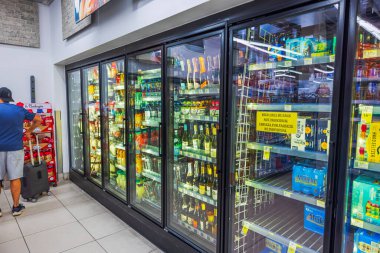 CVS mağazasının içecek dolabı, içki şişeleri ve ürün seçen müşterilerin yakın görüntüsü. Miami Plajı. ABD.