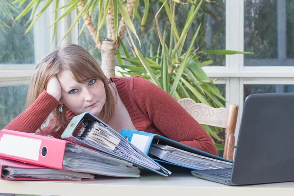 Overwerkt jonge vrouw zit in office — Stockfoto