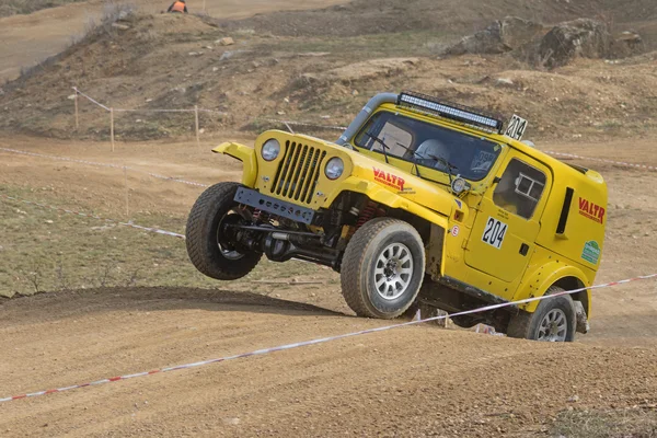 Yellow off road car is jumping in terrain — Stock Photo, Image