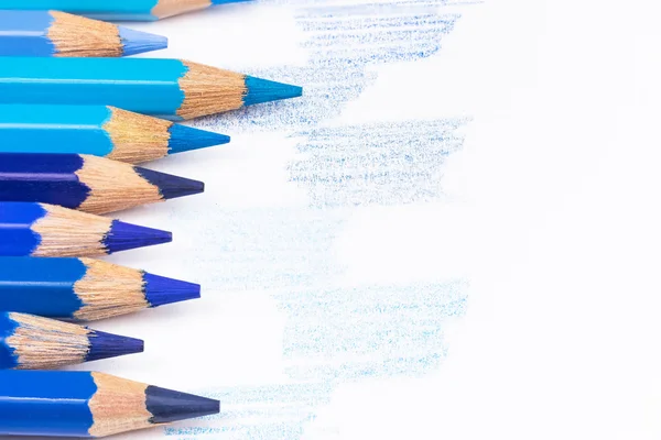 Синие цветные карандаши и нарисованные голубые образцы — стоковое фото