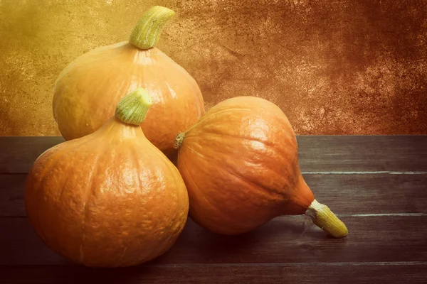 Three pumpkins lying on the wooden desk — Stock Photo, Image