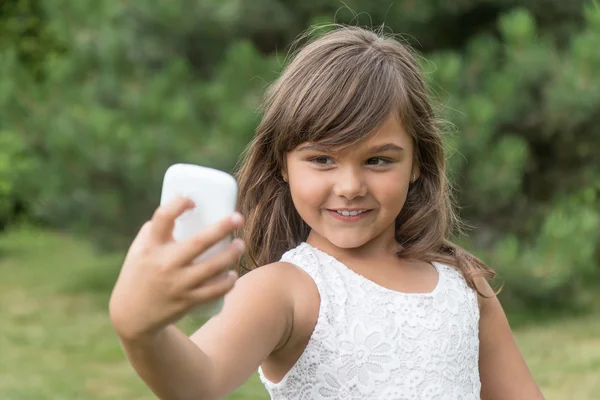 Sonriendo niña atractiva está haciendo selfie —  Fotos de Stock