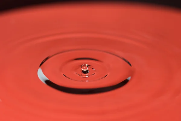 Närbild av fallande vattendroppe i rött — Stockfoto