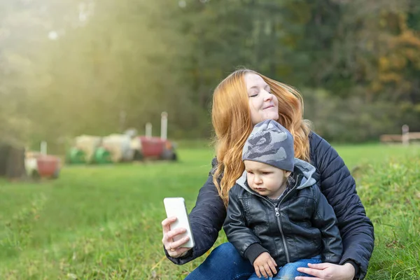 Jovem Mãe Ruiva Com Seu Filhinho Está Fazendo Selfie Parque — Fotografia de Stock