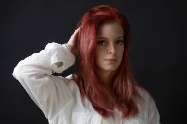 Saçında el olan güzel kızıl saçlı genç bir kadının sade portresi. Yatay olarak. 