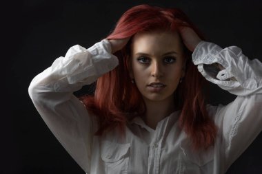 Saçında iki eli olan güzel kızıl saçlı genç bir kadının sade portresi. Yatay olarak. 